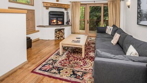 Ein Wohnzimmer mit Kamin, einer Couch, einem Couchtisch und einem großen Fenster.