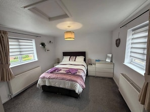 A bedroom with a bed, bedside tables, a lamp, and a radiator.