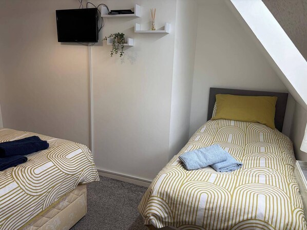 A bedroom with two beds, a TV, and a small plant. - Sleeps 5 pet Friendly, Enclosed Garden, Parking (Hereford)