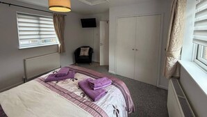 Ein Schlafzimmer mit einem Bett, einem Sessel, einem Fernseher und einem Kleiderschrank.