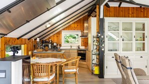 Una cocina con armarios de madera, una mesa de comedor con sillas y vistas a través de una ventana.