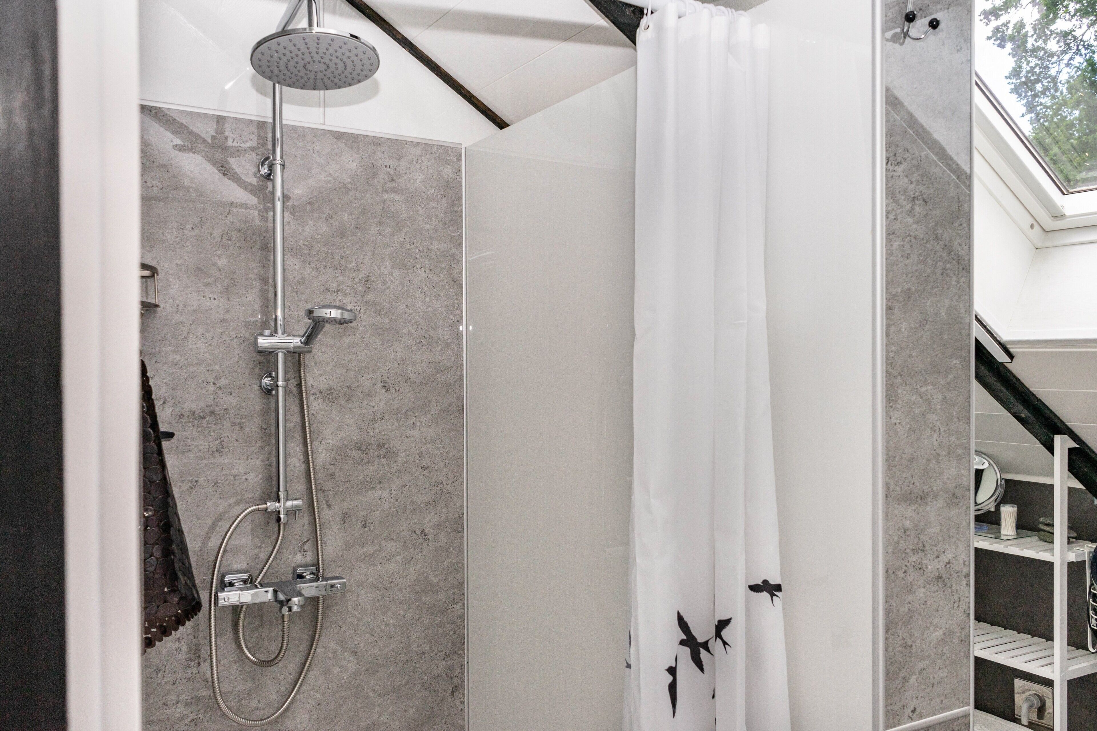 A modern shower with a rain showerhead, a handheld showerhead, and a glass-enclosed shower stall.