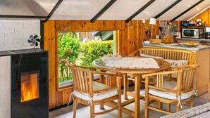 Un interior acogedor de madera con una mesa de comedor, sillas, una chimenea y una zona de cocina.
