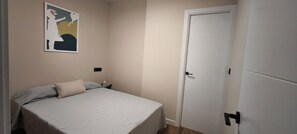 Un dormitorio con una cama, una puerta y una obra de arte colgada en la pared.