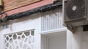 En byggnad med en vit dörr, en ventilationsanläggning och en övervakningskamera.