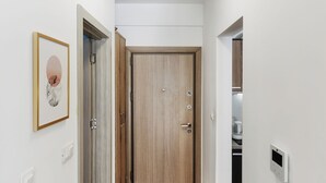 Ein Flur mit einer Holztür, einem Lichtschalter und einem gerahmten Bild an der Wand.
