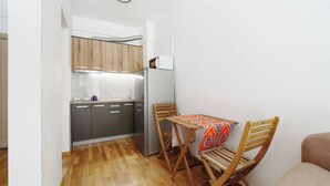 Eine kleine Küche mit Holzausstattung, einem Edelstahlkühlschrank und einem Esstisch mit Stühlen.