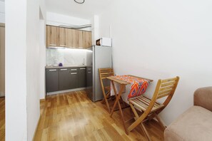 Eine kleine Küche mit Holzausstattung, einem Edelstahlkühlschrank und einem Esstisch mit Stühlen.