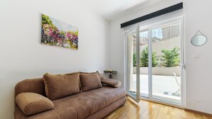 Ein Zimmer mit einem braunen Sofa, einem Blumenbild, einer Schiebetür und einem kleinen Tisch.