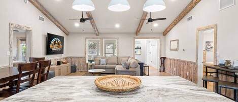 A spacious kitchen with a marble island, wooden beams, and pendant lighting.