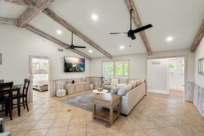 A spacious living room with a sofa, a coffee table, and a dining area with chairs. There are ceiling fans and recessed lighting. - About Time-3BR/4BA Pet Friendly,Private Pool (St. George Island)