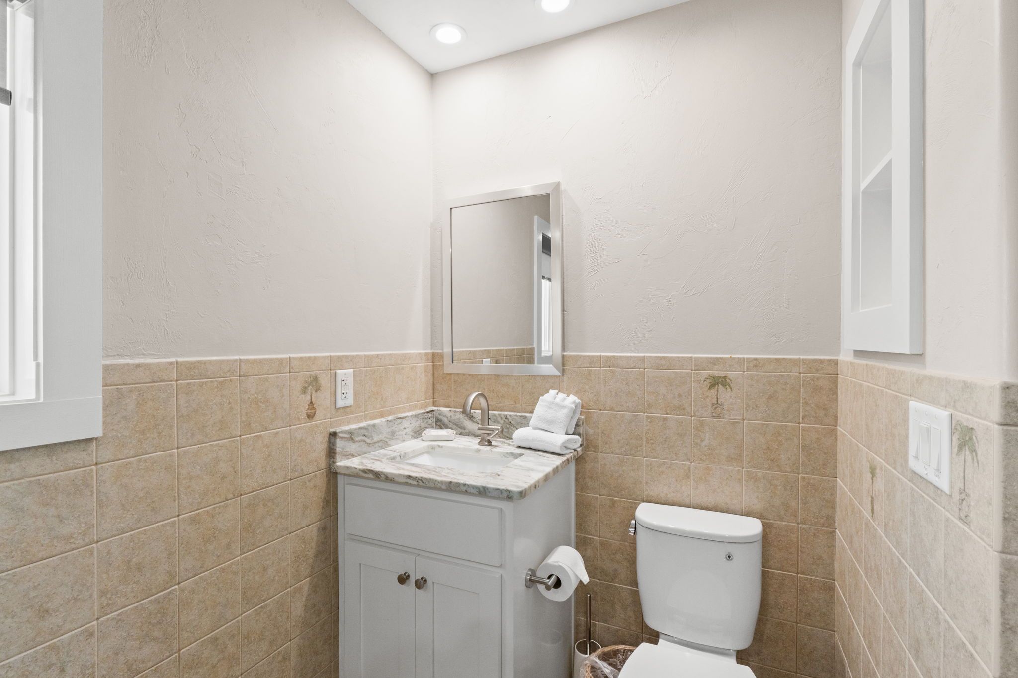 A bathroom with a sink, toilet, and a mirror.