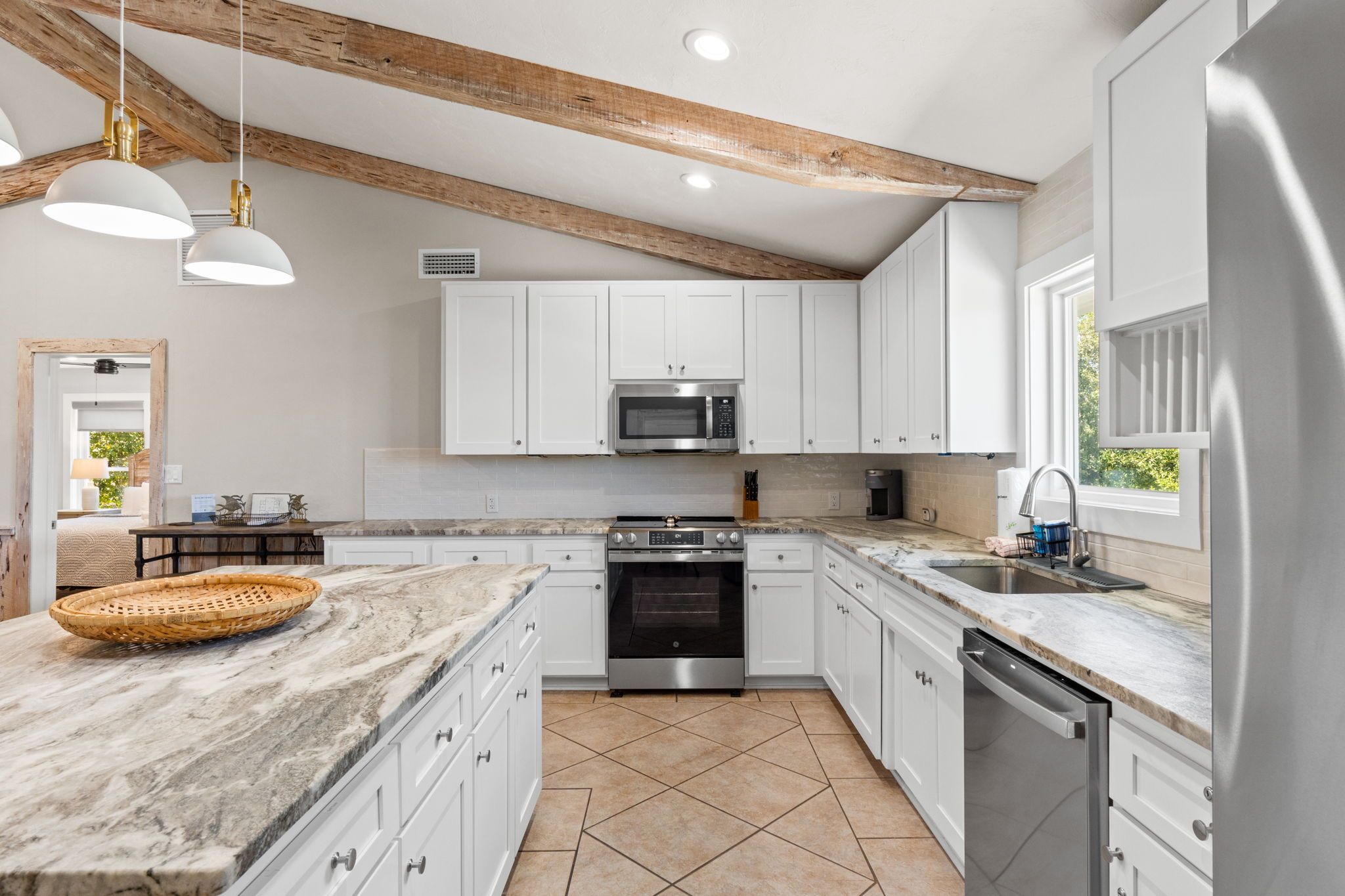 A modern kitchen with white cabinets, a stainless steel oven, and a marble countertop.
