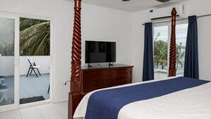 Une chambre à coucher comprenant un lit, une télévision, une commode et un balcon avec une chaise.