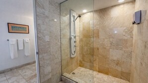 Une salle de bain moderne avec une douche à parois de verre, des carreaux de marbre et un tableau encadré au mur.