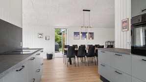 A modern kitchen with a dining area, featuring a large island, black chairs, and a view of the outdoors. - Newly renovated holiday home near the water (Hadsund)