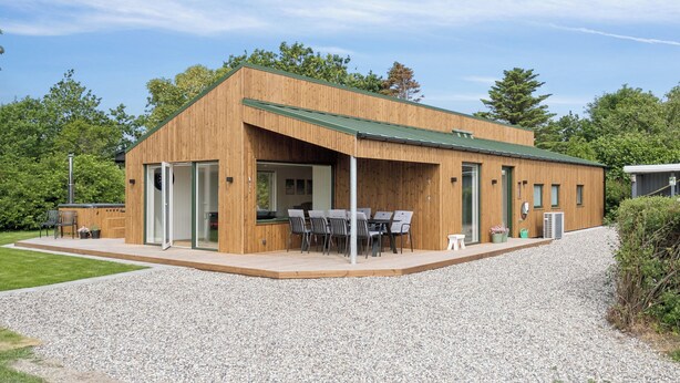 A modern wooden building with a covered patio, outdoor seating, and a gravel driveway. - Newly renovated holiday home near the water (Hadsund)