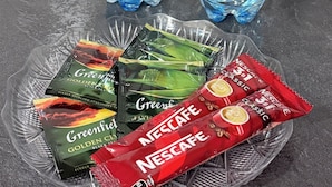 Dos botellas de agua Woto y un plato con té Greenful y sobres de café instantáneo Nescafé.