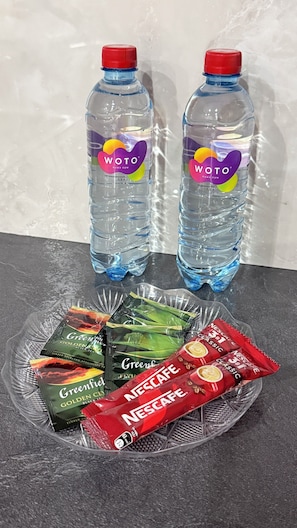 Two Woto water bottles and a plate with Greenful tea and Nescafe instant coffee packets.
