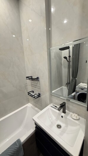 A modern bathroom with a bathtub, a sink with a mirror, and a shower area.