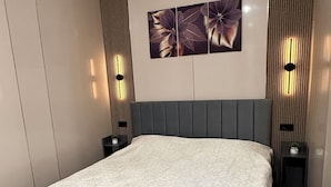 Un dormitorio moderno con una cama grande, cabecera con líneas verticales e iluminación empotrada.