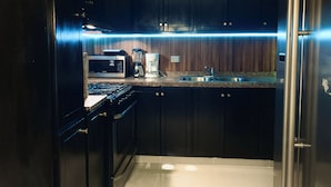 Una cucina con mobili scuri, un forno a microonde, una macchina da caffè e un lavello in acciaio inossidabile.