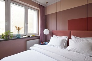 Ein Hotelzimmer mit einem Bett, einem Fenster mit Vorhängen, einem Nachttisch mit Lampe und einem Heizkörper.
