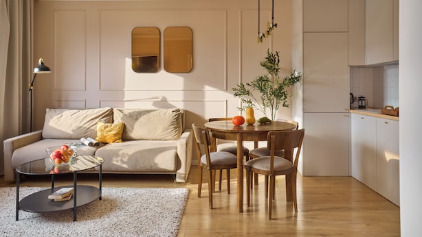 Un salon moderne comprenant un canapé, une table basse, une table à manger et des chaises. Il y a également un coin cuisine avec des placards et un plan de travail.