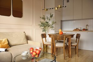A modern kitchen with a dining table, chairs, a glass coffee table with apples, and a vase with greenery. - Polka Bright 2-Bed by Fragola Apartments (Kraków)