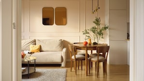 Un salon comprenant un canapé, une table à manger avec des chaises, une petite table d’appoint et une plante.