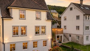 Un edificio residenziale a più piani con tetto a falde, numerose finestre e una scala visibile che conduce all'ingresso.