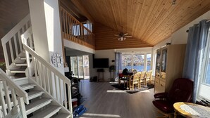 A spacious living area with a wooden ceiling, a dining table, and a view of the water. - Lofoten Villa by the sea (Vågan)