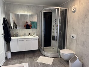 A modern bathroom with a glass-enclosed shower, a white sink with a mirror, and a toilet.