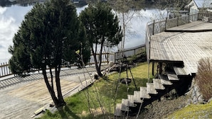 A lakeside property with a wooden deck, a staircase, and a view of the surrounding houses. - Lofoten Villa by the sea (Vågan)