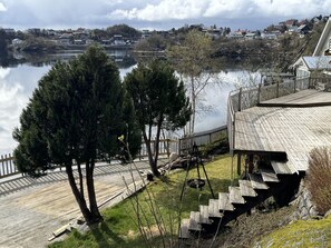A lakeside property with a wooden deck, a staircase, and a view of the surrounding houses.