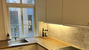 A modern kitchen with a built-in sink, wooden countertop, and white cabinets. - Central apartment close to Bryggen (Bergen)