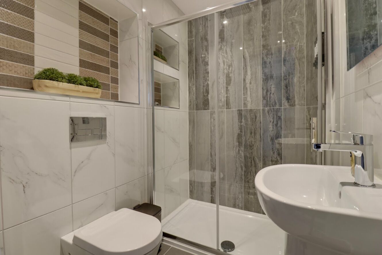 Een moderne badkamer met toilet, douche en wastafel.