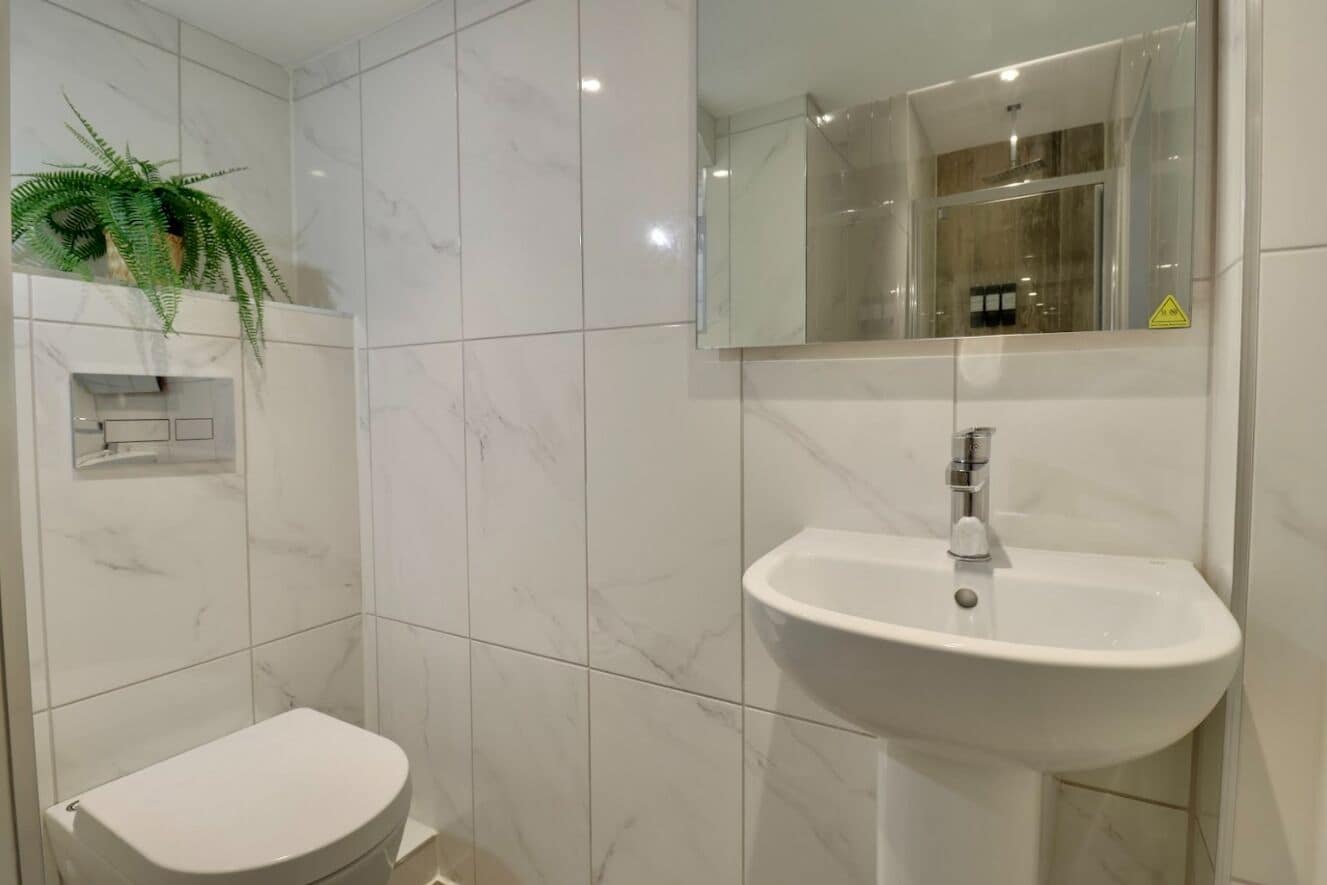 A bathroom with a toilet, a sink, and a mirror.