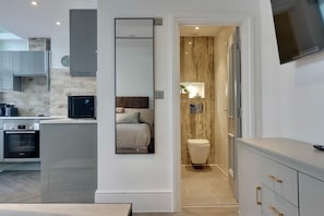 A modern kitchen with built-in appliances, a dining area, and a bathroom with a marble vanity. - QE2 Loft Apartments (Southampton)