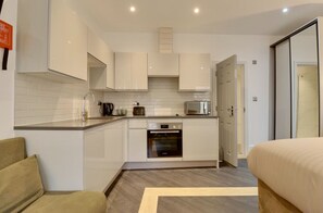 A compact kitchen with white cabinets, a built-in oven, and a microwave.