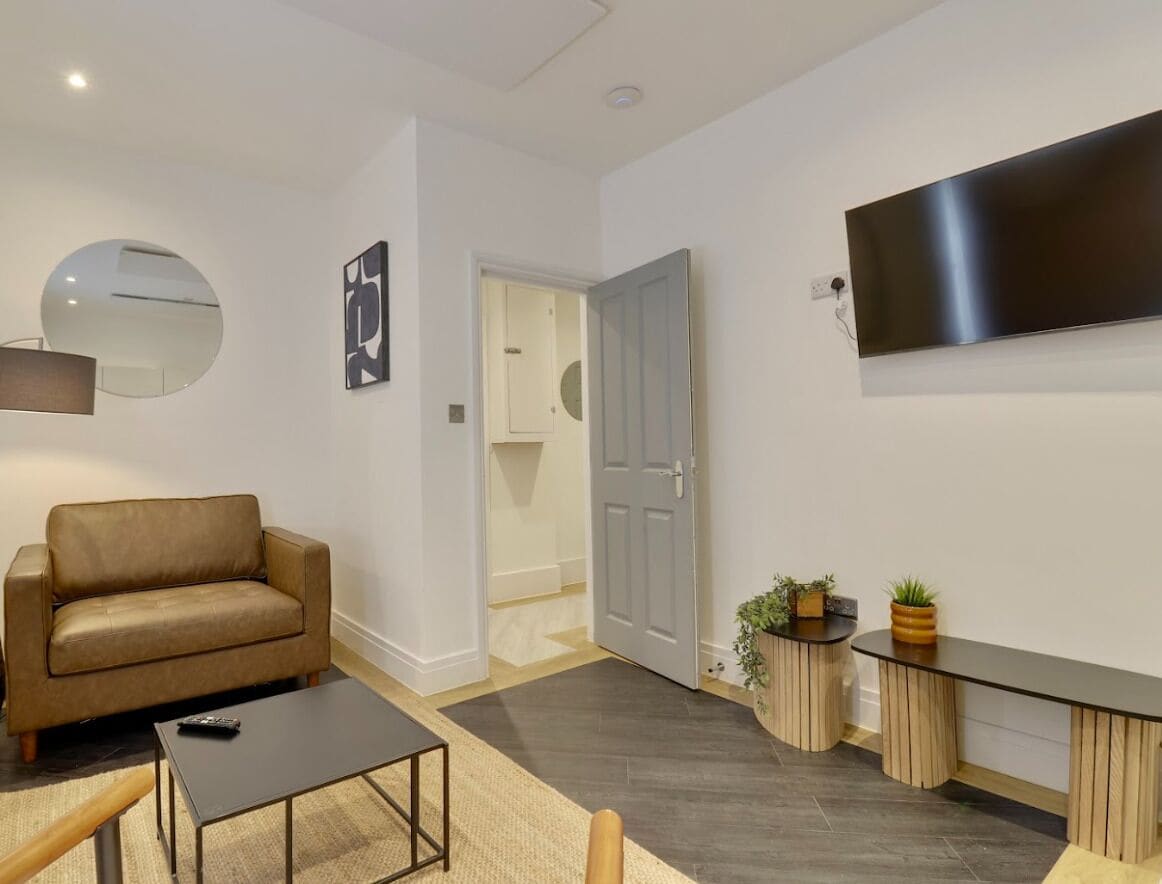 A living room with a sofa, coffee table, TV, and a door leading to another room.