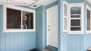 A blue house with a white door, a number 311 sign, and a small porch with steps.