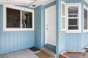 Ein blaues Haus mit weißer Tür, einer Hausnummer 311 und einer kleinen Veranda mit Stufen.