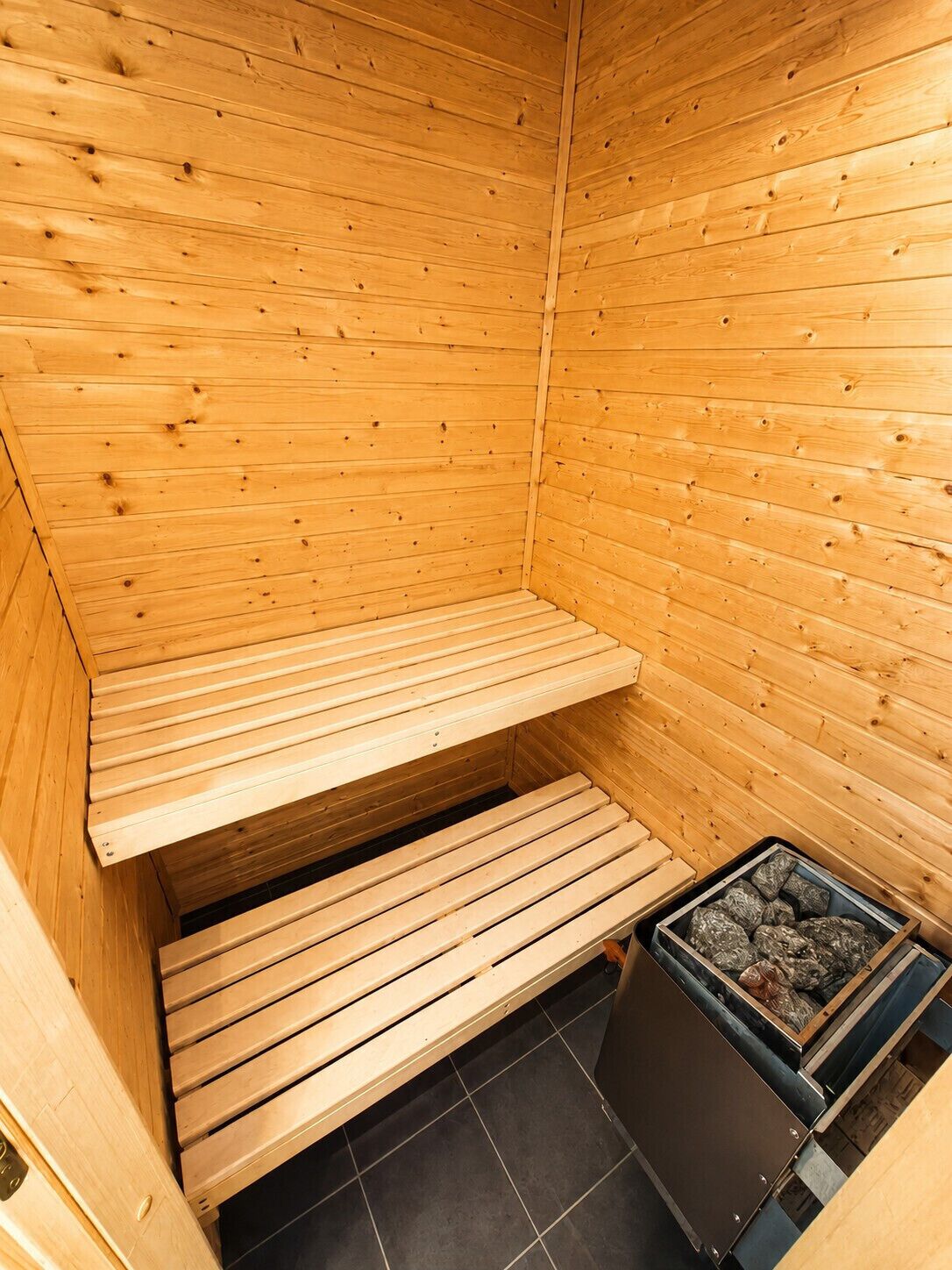 Sauna, jossa on puiset lauteet ja kivistä tehty lämmityselementti.