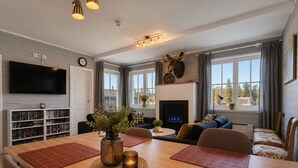 A modern living room with a fireplace, a mounted deer head, a bookshelf, and a television. - Golsfjellet Apartment with Sauna (Gol)