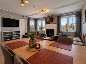 Un salon moderne avec une cheminée, une tête de cerf montée au mur, une bibliothèque et un téléviseur.