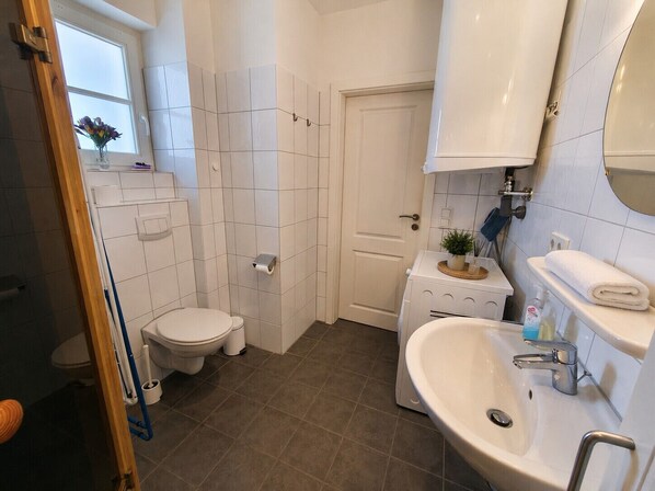 Une salle de bain comprenant des toilettes, un lavabo et un espace douche.