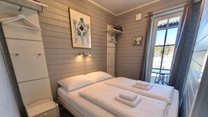 A double bed with white linens, a bedside table, a hanging coat rack, a framed picture on the wall, and a window with curtains. - Golsfjellet Apartment with Sauna (Gol)