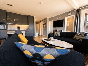 Un salon moderne avec un canapé, une table basse et un téléviseur à écran plat.
