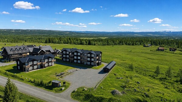 A lodge with multiple buildings, a paved driveway, and a surrounding grassy landscape.